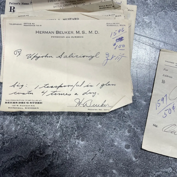 Old handwritten prescription notes on weathered paper against a metallic surface, featuring detailed dosage instructions and a doctor's signature.