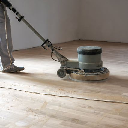 Floor CarePerson operating a floor sanding machine on a wooden floor, smoothing the surface. The setting is indoors with a calm, focused atmosphere.
